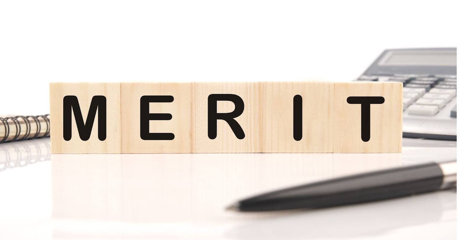 デスクの上に「MERIT」と書かれた積み木が置いてある。周りには電卓やメモ帳、ペンもある。