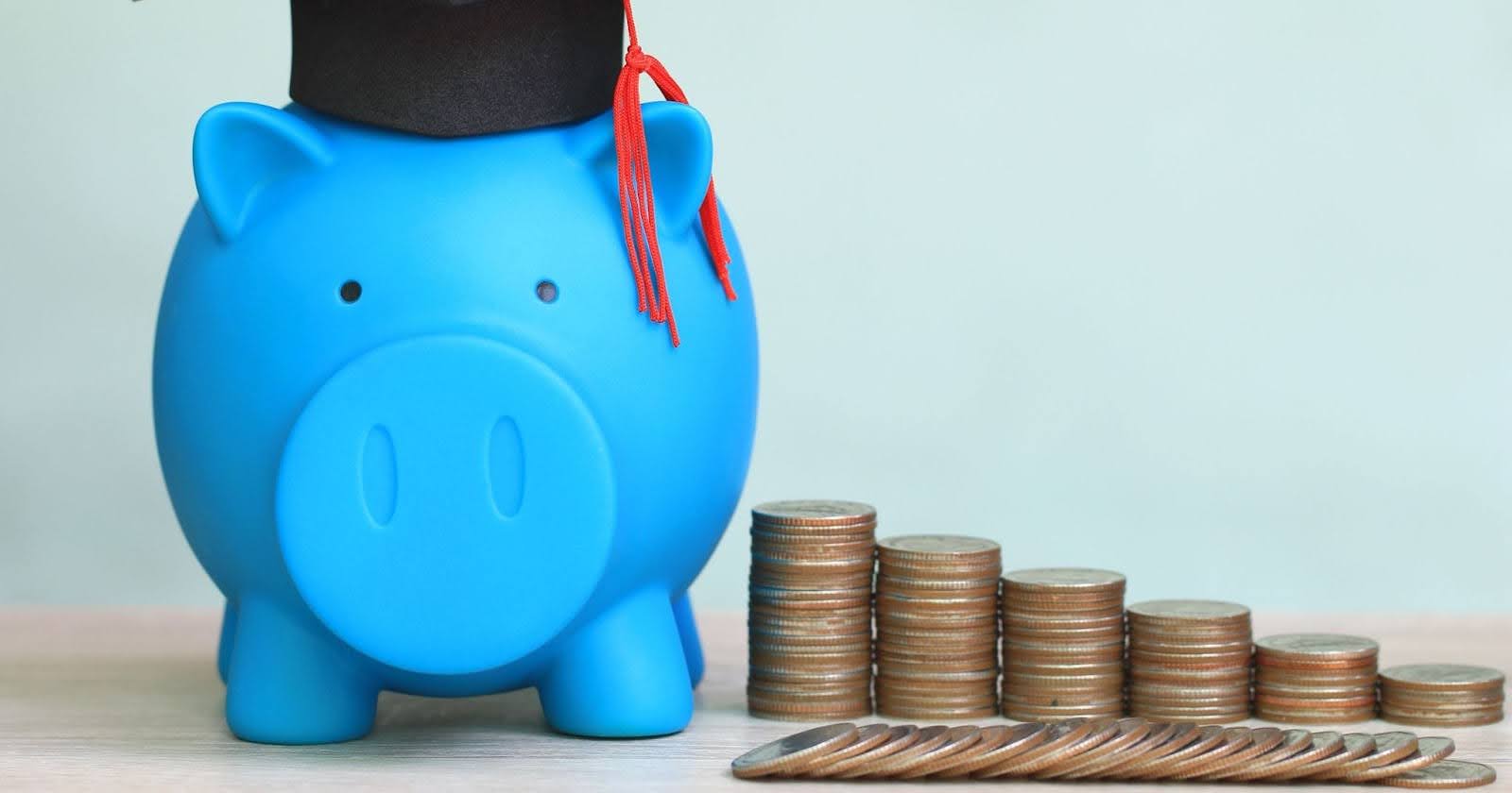 青いブタの貯金箱と積み上がったコイン。リーズナブル・節約のイメージ写真